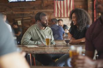Young Couple Meeting In Sports Bar Enjoying Drink Before Game