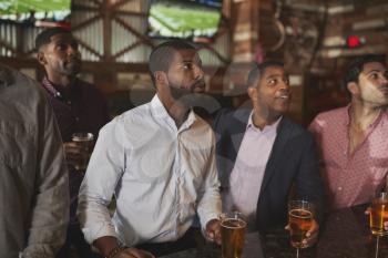Group Of Male Friends On Night Out For Bachelor Party Watching Screens