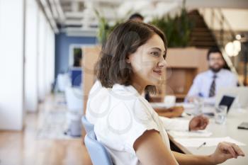 Businesswoman With Colleagues Sitting At Table Listening To Presentation In Modern Office
