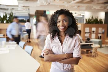 Portrait Of Businesswoman In Busy Modern Office With Blurred Colleagues Working In Background