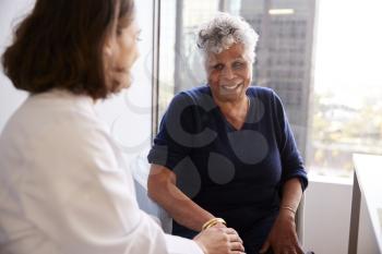 Female Doctor In Office Reassuring Senior Woman Patient And Holding Her Hands