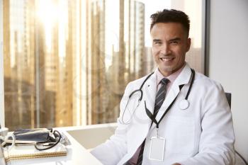 Portrait Of Smiling Male Doctor Wearing White Coat With Stethoscope In Hospital Office