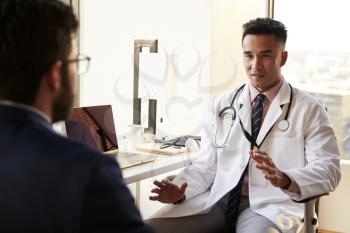 Over The Shoulder View Of Man Having Consultation With Male Doctor In Hospital Office