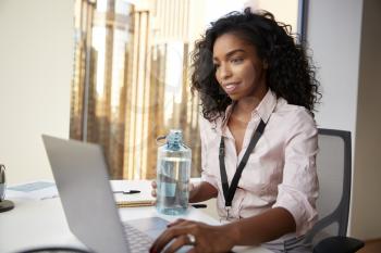 Businesswoman With Laptop Sitting At Desk Keeping Hydrated Drinking From Water Bottle In Office