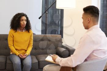 Woman Sitting On Couch Meeting With Male Counsellor In Office