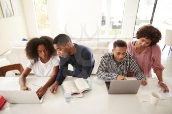 Middle aged black parents helping their teenage kids using laptops to do homework, elevated view