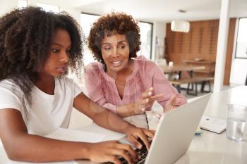 Middle aged black woman helping her teenage daughter with homework, close up