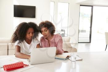 Middle aged black woman helping her teenage daughter with homework, front view