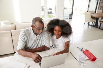 Teenage black girl helping her grandfather use a laptop computer at home, elevated view