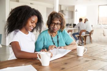Teenage black girl looking through a photo album with her grandmother at home, close up