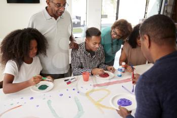 Three generation black family making a sign for a surprise party together at home, close up