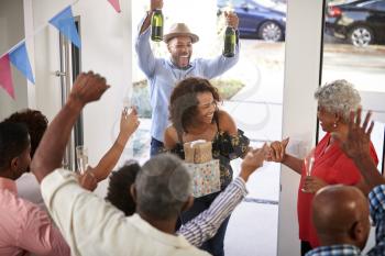Three generation family throwing a surprise party welcoming guests at the front door,elevated view