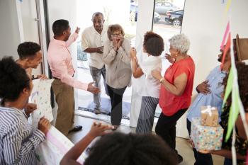 Senior black couple arriving home to a family surprise party, elevated view