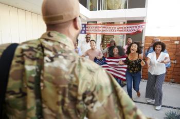 Three generation black family welcoming soldier returning home,over shoulder view