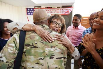 Millennial black soldier returning home to his family, embracing grandmother, back view