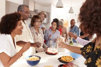 Senior black woman blowing out the candle on birthday cake during a celebration with her family