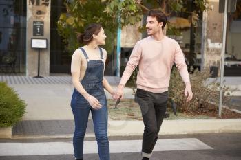 Millennial hipster couple crossing the road in the city holding hands, close up