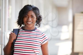 Portrait Of Smiling Female University Student With Backpack In Corridor Of College Building