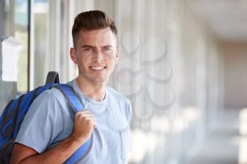 Portrait Of Smiling Male University Student With Backpack In Corridor Of College Building