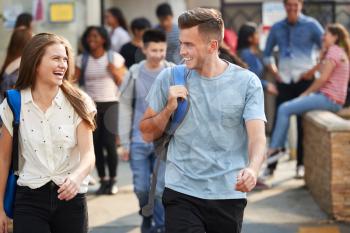 Group Of Smiling Male And Female College Students Walking And Chatting Outside School Building