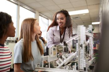 Woman Teacher With Female College Students Building Machine In Science Robotics Or Engineering Class