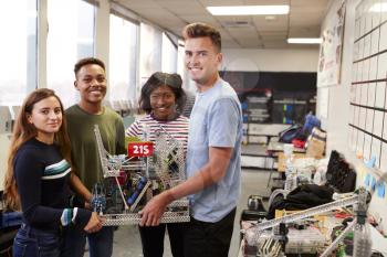 Portrait Of University Students Carrying Machine In Science Robotics Or Engineering Class