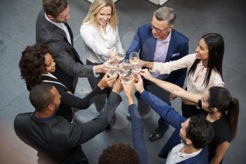 Overhead Shot Of Business Team Celebrating Success With Champagne Toast In Modern Office