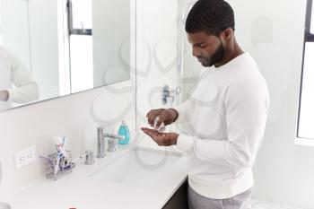 Man In Bathroom Taking Vitamin Supplement Tablets