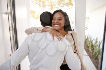 Man Greeting And Hugging Businesswoman Wife As She Returns Home From Work
