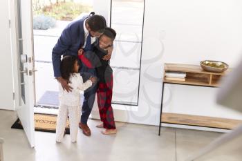 Children Greeting And Hugging Working Businessman Father As He Returns Home From Work