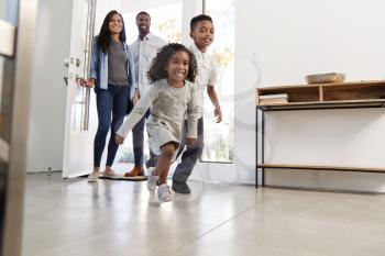 Parents And Children Returning Home Opening Front Door And Running Inside