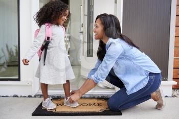 Mother Tying Daughters Shoelaces As She Leaves For School