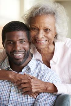Portrait Of Smiling Senior Mother Hugging Adult Son At Home