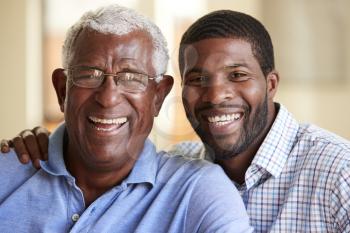 Portrait Of Smiling Senior Father Being Hugged By Adult Son At Home