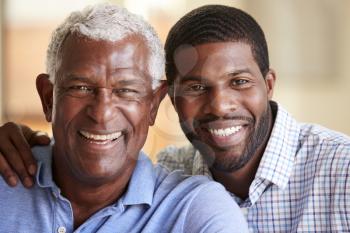 Portrait Of Smiling Senior Father Being Hugged By Adult Son At Home