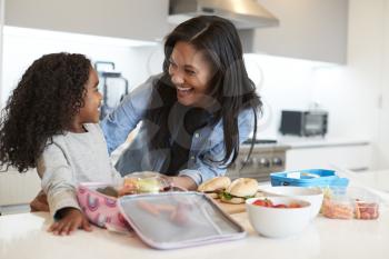 Daughter In Kitchen At Home Helping Mother To Make Healthy Packed Lunch
