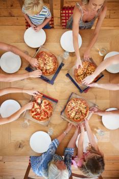 Overhead View Of Multi Generation Family Sitting Around Table Eating Pizza Together