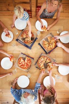 Overhead View Of Multi Generation Family Sitting Around Table Eating Pizza Together