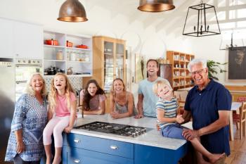 Portrait Of Multi Generation Family Standing Around Kitchen Island Together