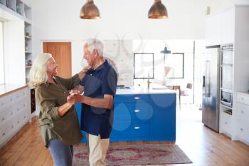 Senior Couple At Home Dancing In Kitchen Together