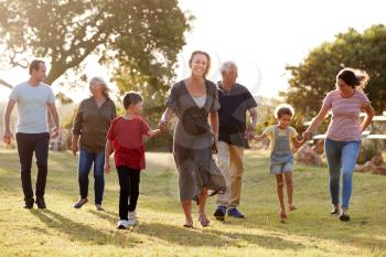 Multi-Generation Family Walking In Countryside Against Flaring Sun