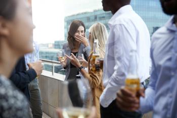Office colleagues socialising with drinks on a balcony in the city after work