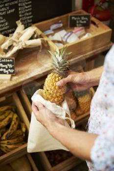 Close Up Of Man Putting Pineapple Into Reusable Cotton Bag In Plastic Free Grocery Store