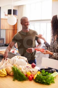 Couple Returning Home From Shopping Trip Unpacking Plastic Free Grocery Bags