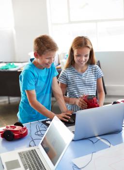 Two Students In After School Computer Coding Class Learning To Program Robot Vehicle