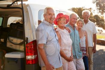 Portrait Of Senior Friends Standing Together Beside Van On Vacation