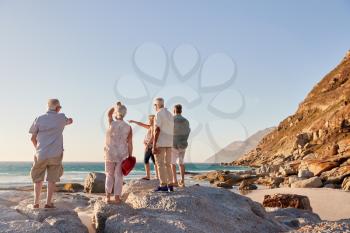 Rear View Of Senior Friends Standing On Rocks On Summer Group Vacation Looking Out To Sea