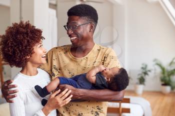 Loving Parents Holding Newborn Baby At Home In Loft Apartment
