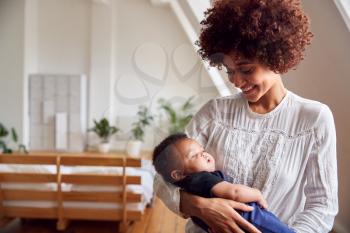 Loving Mother Holding Newborn Baby At Home In Loft Apartment