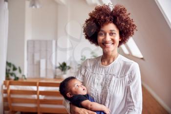 Portrait Of Loving Mother Holding Newborn Baby At Home In Loft Apartment